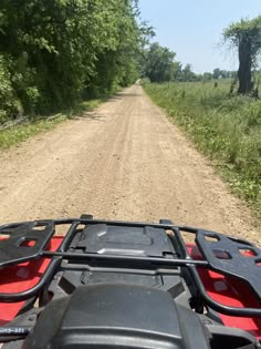 an atv driving down a dirt road in the woods