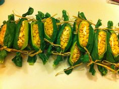 corn on the cob with green leaves and yellow kernels are laid out on a cutting board