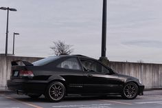 a black car parked in a parking lot next to a light pole and street lamp