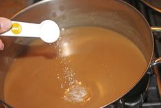 a person is stirring something in a pot on the stove with a white spatula