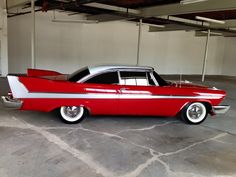 an old red and white car parked in a garage