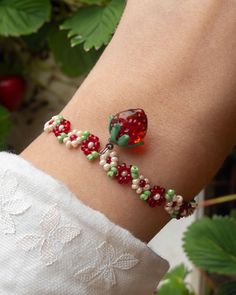 a close up of a person's arm wearing a bracelet with fruit on it