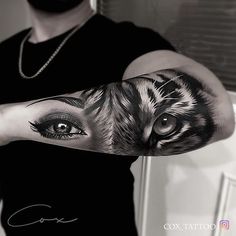 a man with a tiger tattoo on his arm and eye looking at the camera while wearing a black t - shirt