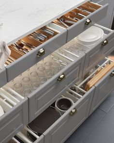 an open drawer with dishes and utensils in it on the side of a kitchen counter