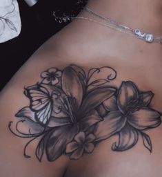 a woman's back tattoo with flowers and butterflies on her left side, in black and white