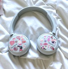 a pair of headphones sitting on top of a white bed covered in pink stickers