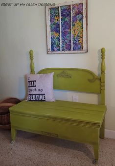 a green bench sitting in front of a window with a pillow on top of it