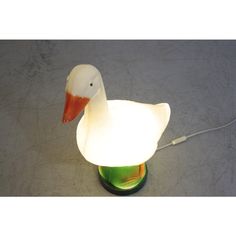 a white duck lamp sitting on top of a green glass table next to a light bulb