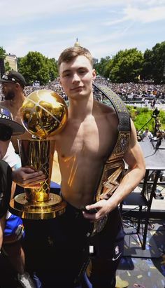 a shirtless man holding up a trophy