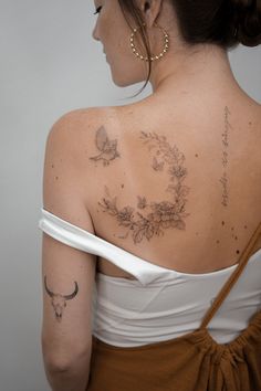 the back of a woman's shoulder with tattoos on her upper half and lower half