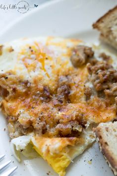 an egg casserole with sausage and cheese on a white plate next to a slice of bread