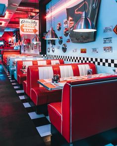 the interior of a diner with checkered flooring and red booths, black and white walls