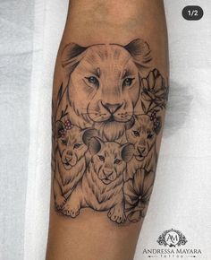 a lion and two cubs tattoo on the right calf's leg with flowers around it