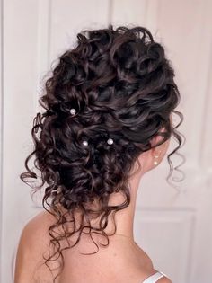 the back of a woman's head with curly hair and pearls in her hair