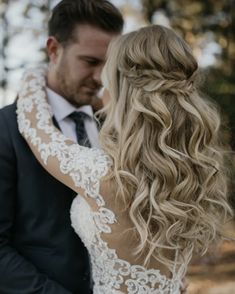 a bride and groom embracing each other in front of some trees with their arms wrapped around them