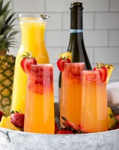 three glasses filled with orange juice and strawberries