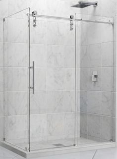 a walk in shower sitting next to a white tiled wall and floor with a glass door