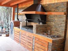 an outdoor kitchen with a large oven and grill on the outside wall next to it