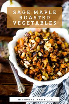 a white bowl filled with roasted vegetables on top of a wooden table next to silverware