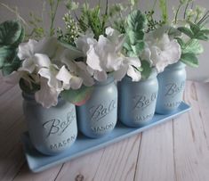 three blue mason jars with white flowers in them