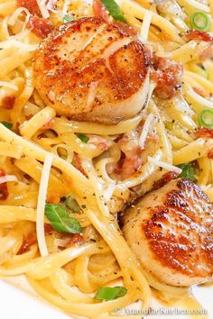 a white plate topped with pasta and scallops