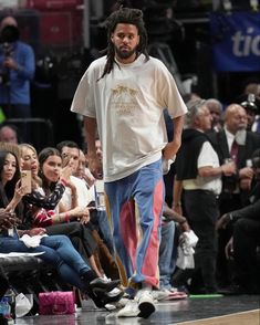 a man with dreadlocks is walking on the court while people watch from the sidelines