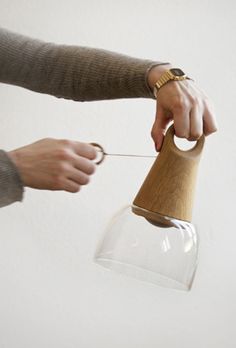 a person is holding a wooden object in their hand and pulling it out of a glass vase