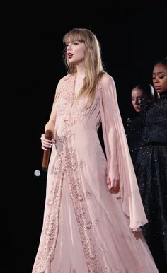 a woman in a pink dress standing next to two other women