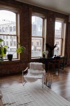 a living room filled with lots of windows next to a white rug on top of a hard wood floor