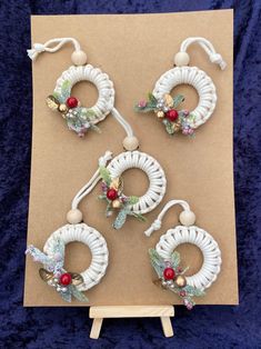 four christmas wreaths are hanging on a piece of brown paper with white string and beads