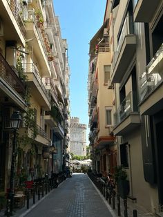 an empty city street with buildings and balconies on both sides, surrounded by greenery