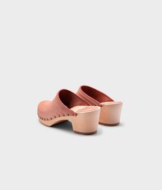 Made by skilled artisans in Sweden, these blush pink nubuck clog mules feature a high heel and eye-catching stud detailing on the sides. From date nights to ladies' nights out, Rome delivers unparalleled style and confidence. Clog measurements:Heel height: 2 5/8” (6.5 cm)Toe height:﻿ 1 1/2″ (3.8 cm) Fit:NarrowLeather:Nubuck leatherClogs consist of:Base: European Lime Wood Sole: Rubber sole Fastening: Brass studs Spring Slip-on Clogs With Studded Rubber Outsoles, Suede Slip-on Mules With Wooden Heel, Summer Slip-on Clogs With Sculpted Heel, Suede Mules With Sculpted Heel And Round Toe, Spring High Heel Clogs With Studded Rubber Outsoles, Summer Clogs With Leather Sole And Almond Toe, Summer Almond Toe Clogs With Leather Sole, Pink Leather Slip-on Mules, Suede Clogs With Stacked Open Heel