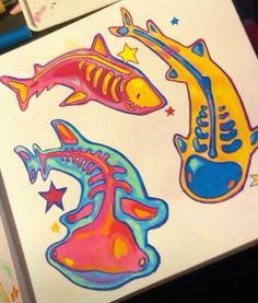 two colorful fish stickers sitting on top of a piece of paper