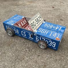 a toy car made out of license plates on the ground next to a parking meter