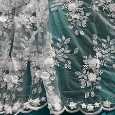 Add a touch of ethereal romance and innocent charm to your next special event with our high-quality Beaded 3D Floral Lace Fabric. This exquisite design, embroidered on 100% polyester net mesh, features 3D satin flowers, each adorned with a delicate pearl at its heart. The design is further enriched by beautifully embroidered leaves that add a touch of nature's elegance. Symmetrical scallops frame the design, decorated with multi sized raised 3D flowers, each one embellished with a pearl beading Elegant Lace Fabric With 3d Embroidery, Elegant Floral Embellished Lace Fabric, Elegant Organza Lace With Floral Embroidery, Elegant Floral Embroidered Organza Lace, Elegant Floral Embroidery Organza Lace, Elegant Organza Fabric With 3d Embroidery, Elegant Embroidered Organza Lace, Elegant Embroidered Tulle Fabric For Spring, Elegant Floral Applique Lace For Wedding