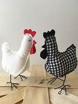 two stuffed chickens are standing next to each other on a wooden table with white walls in the background