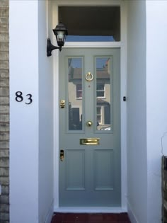 the front door is painted blue and has two lights on each side, along with a brick wall