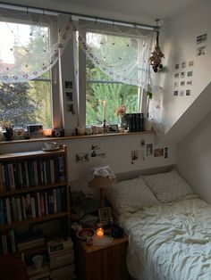 a bed sitting under a window next to a bookshelf filled with lots of books