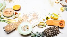 an assortment of fruits and vegetables on a white surface with sprinkles around them