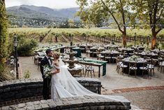 a bride and groom pose for a photo in front of the vineyard at their wedding