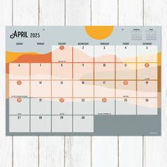 a calendar on a wooden surface with the month marked in orange and yellow colors, as well as an image of mountains