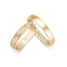 two gold wedding bands with floral designs on them, one is in the shape of a heart