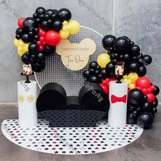 mickey mouse balloon arch with black and red balloons on top, white pillars in the middle