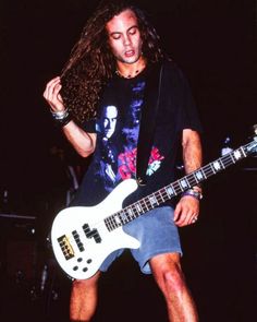 a man with long hair playing an electric guitar