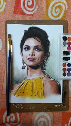 a drawing of a woman in yellow dress next to some watercolors and a brush