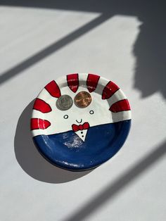 a penny is placed in the center of a small blue and white plate with red stripes on it