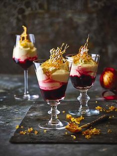 three glasses filled with dessert sitting on top of a table