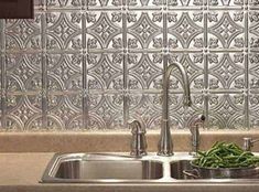 a kitchen sink with some green beans in the bowl next to it and a metal tile backsplash