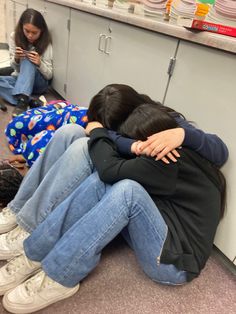 two people sitting on the floor with their arms around each other