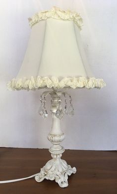 a lamp that is on a table with a white cloth shade and some beads hanging from it